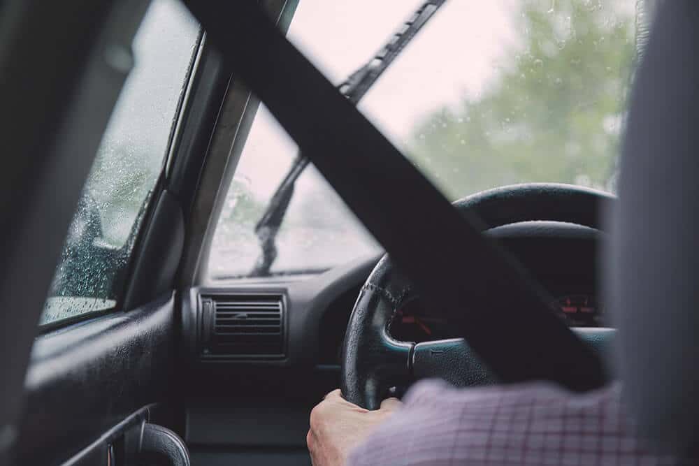 Driver's left shoulder and hand holding steering wheel