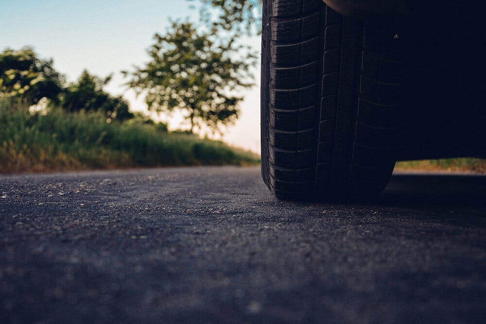 Worm's eye view of car's back tire and road 