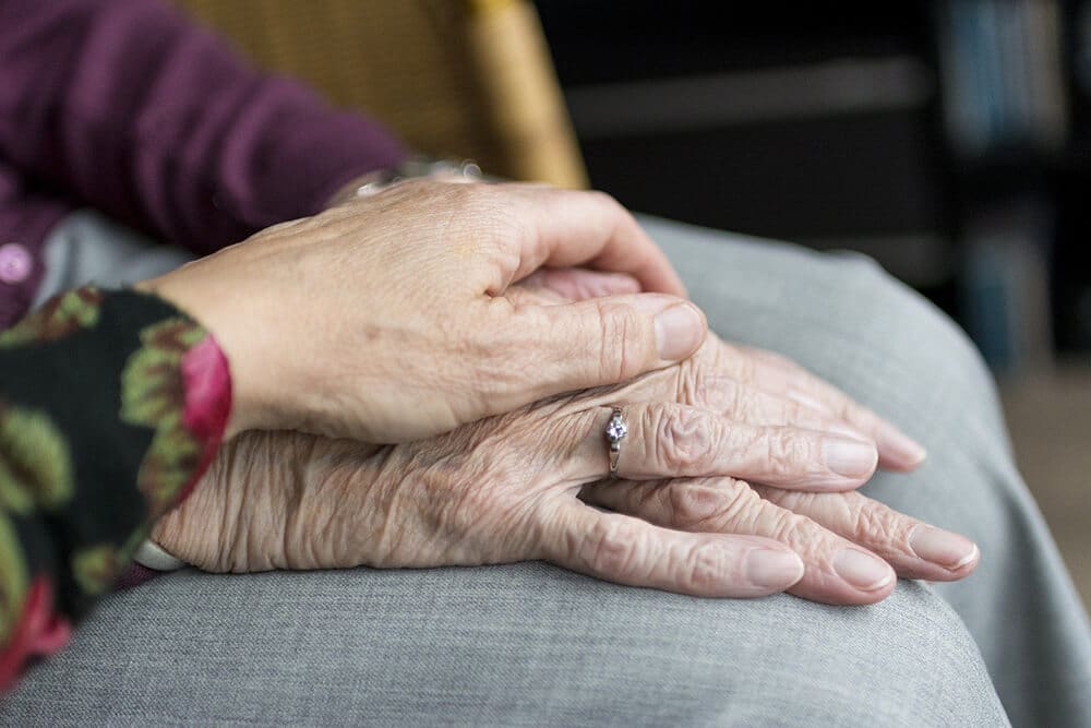 Person putting hand on older person's hands